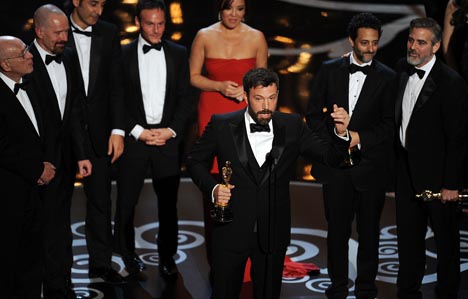 Ben Affleck discursa após a vitória de "Argo", sob os olhares atentos do produtor George Clooney.
