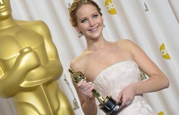 Depois de cair, Jennifer Lawrence exibe o seu valioso prêmio.